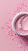 Pink cosmetic cream in white jar surrounded by decorative sugar pearls on pastel pink background, top view. Suitable for beauty product advertising.
