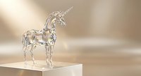 Crystal clear glass unicorn figurine standing on white pedestal against soft beige background for home decor and fantasy collectibles.