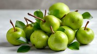 Fresh green apples with stems and leaves arranged on light surface, showcasing natural texture and vibrant color for food photography and healthy eating concepts.