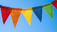Colorful triangular bunting flags hanging against clear blue sky for festive celebrations, parties, outdoor events and decorative purposes.