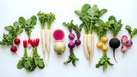 Fresh organic radishes and turnips with green leaves arranged in colorful row on white background, perfect for healthy cooking and farm-to-table recipes.