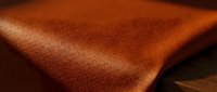 Warm terracotta leather texture with natural light creating dimensional shadows and highlights, suitable for backgrounds, design projects, and material references.