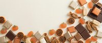 Assorted luxury chocolates and confections arranged on cream background with copy space for dessert and confectionery designs.