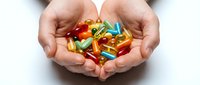 Hands holding colorful vitamin capsules and supplements on white background. Suitable for healthcare, wellness, nutrition and medical content.