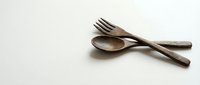 Wooden fork and spoon utensils set on neutral background for kitchen dining and cooking concepts. Natural wood cutlery for eco-friendly sustainable lifestyle.