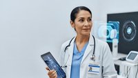 Female doctor holding tablet with digital interface in modern medical office with advanced technology displays for healthcare innovation.