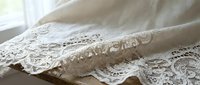 White vintage lace fabric with intricate floral patterns and delicate trim details on soft textile background for romantic wedding decor projects.