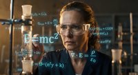Female scientist in safety glasses analyzing mathematical formulas and equations in modern laboratory for research and education.