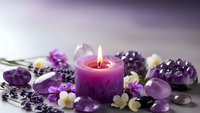 Purple candle burning surrounded by amethyst crystals, lavender flowers and gemstones creating peaceful spa atmosphere for relaxation and wellness.