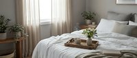 Cozy bedroom interior with white bedding, wooden breakfast tray, plants and natural light creating peaceful morning atmosphere for home decor and lifestyle.