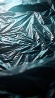 Crumpled aluminum foil texture with metallic reflections and wrinkled surface creating abstract patterns for packaging and industrial design backgrounds.