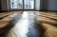 Sunlight streaming through window creates dramatic shadows on herringbone parquet flooring in modern apartment interior, low angle perspective with selective focus.