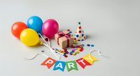 Colorful balloons, party hat, gift box, and confetti with festive banner on white background, suitable for birthday celebrations and event planning designs.