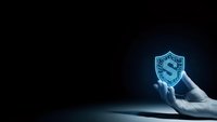 Hand holding glowing blue cybersecurity shield with dollar sign on dark background for financial protection and digital security concepts.