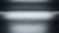 Brushed metal surface with dramatic lighting creating gradient shadows and highlights for modern industrial design backgrounds.