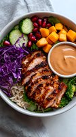 Grilled chicken bowl with butternut squash, red cabbage, cucumber, pomegranate seeds, rice and creamy sauce. Fresh healthy lunch with colorful vegetables.