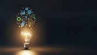 Glowing light bulb with colorful business icons floating above representing innovation, creativity and bright ideas for startup success.
