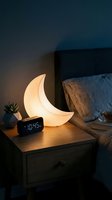 Glowing crescent moon lamp on wooden nightstand beside bed creates cozy ambient lighting for bedroom decor and relaxation.