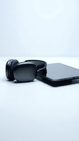 Black wireless headphones and smartphone on white background for technology and audio device marketing materials.