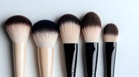 Professional makeup brushes with soft synthetic bristles and wooden handles arranged in row showing size variety on white background for beauty and cosmetics industry.