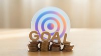 Business goal achievement concept with target symbol and coin stacks representing financial planning and investment strategy for success.