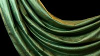 Elegant green metallic fabric with golden edges flowing in smooth waves against black background creating luxurious textile abstract composition.