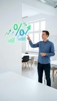 Young man in casual blue shirt pointing at green growth chart with percentage symbols and upward arrows on white wall in modern office space for business analytics and financial success concepts.