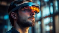 Young bearded man wearing futuristic virtual reality headset with orange reflective display in dark environment with blue lighting.