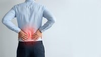 Man in blue shirt holding lower back with red pain highlight, depicting backache, spine injury, or muscle strain in healthcare concept.