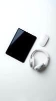Modern workspace essentials with black tablet, white wireless mouse and headphones on clean white background for tech and business projects.