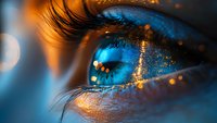 Mesmerizing close-up of blue human eye with golden glitter sparkles and long eyelashes against dark background, artistic macro photography for beauty concepts.