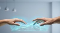 Two hands reaching toward each other with glowing digital connection and data streams between them representing technology collaboration and human interaction.