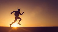 Male runner silhouette sprinting at golden hour sunset with dramatic sky background for fitness and motivation concepts.