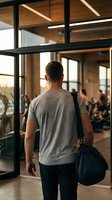 Athletic man with gym bag entering modern fitness center through glass doors for workout session.