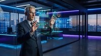 Mature male professional in dark business suit and glasses analyzing digital financial data with holographic charts in modern office environment with neon lighting.