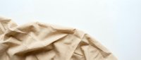 Crumpled beige linen fabric on white background, isolated textile material suitable for design projects, backgrounds, and product mockups.