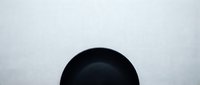 Empty black bowl on white surface, isolated and ready for culinary, food styling, and kitchen design projects.