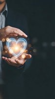 Businessman hands protecting glowing heart symbol with warm light effects representing love, care, health insurance and emotional wellness concepts.