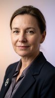 Professional mature businesswoman in dark suit smiling confidently against soft gradient background for corporate headshot and executive portraits.