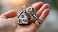 House keys with home-shaped keychain in open palm symbolizing real estate ownership, property purchase, mortgage approval, and new homeowner success.