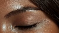Close up macro shot of closed eye with natural makeup, long eyelashes and groomed eyebrow on dark skin tone woman face showing skincare and beauty concept.