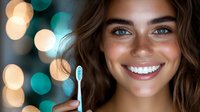 Young woman with bright smile holding toothbrush against blurred bokeh lights background. Dental care and oral hygiene concept for healthy white teeth.