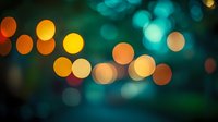 Dreamy bokeh lights in orange, yellow and turquoise colors create magical blurred background with soft glowing circles on dark emerald backdrop.