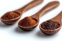 Three wooden spoons with different coffee textures: ground, instant, and whole beans on white background, macro photography showing rich coffee details and textures.