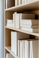 White books arranged on wooden shelves creating minimalist aesthetic composition. Clean monochromatic library setup with soft natural lighting for modern interior design.