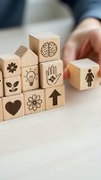 Wooden blocks with engraved symbols including brain, lightbulb, hand, heart and flower icons arranged by person for creative thinking and problem solving concepts.
