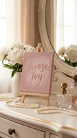 Choose Joy rose gold calligraphy sign on mini easel, elegant vanity with pearls, peonies, and crystal perfume bottles in soft pink decor.