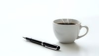 Black fountain pen and white coffee cup on clean white background for business and office design concepts.