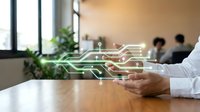 Businessman holding tablet with glowing circuit board hologram overlay, representing digital transformation and technology innovation in modern office environment.