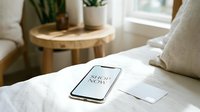 Smartphone with shop now screen on white bed beside credit card, cozy bedroom interior, mobile shopping and e-commerce concept.